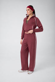 Modella indossa tuta sportiva bordeaux Follower SRL con felpa full zip e pantaloni a gamba larga con righe bianche