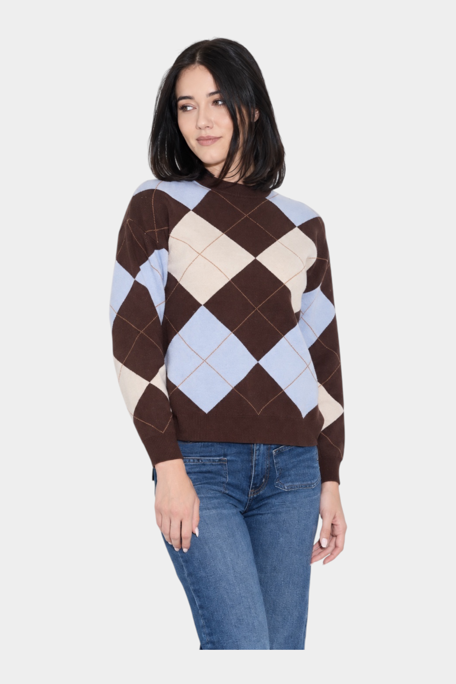 Modella indossa un maglione Follower SRL a rombi marroni, azzurri e crema con girocollo e jeans blu