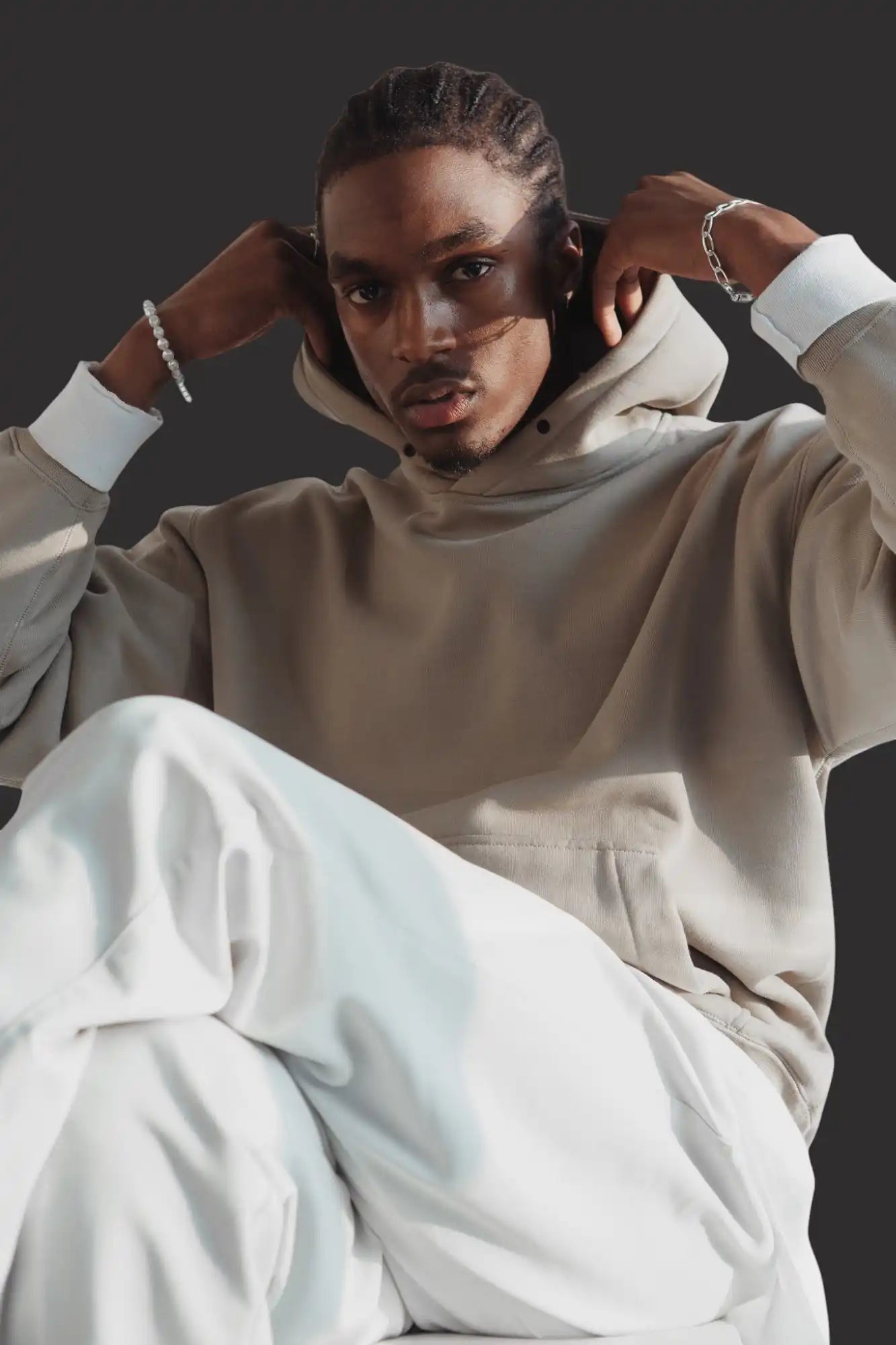 Felpa oversize beige con cappuccio con cordoncino e polsini bianchi.