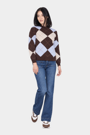 Modella indossa un maglione Follower SRL a rombi marroni e azzurri con jeans blu e sneakers