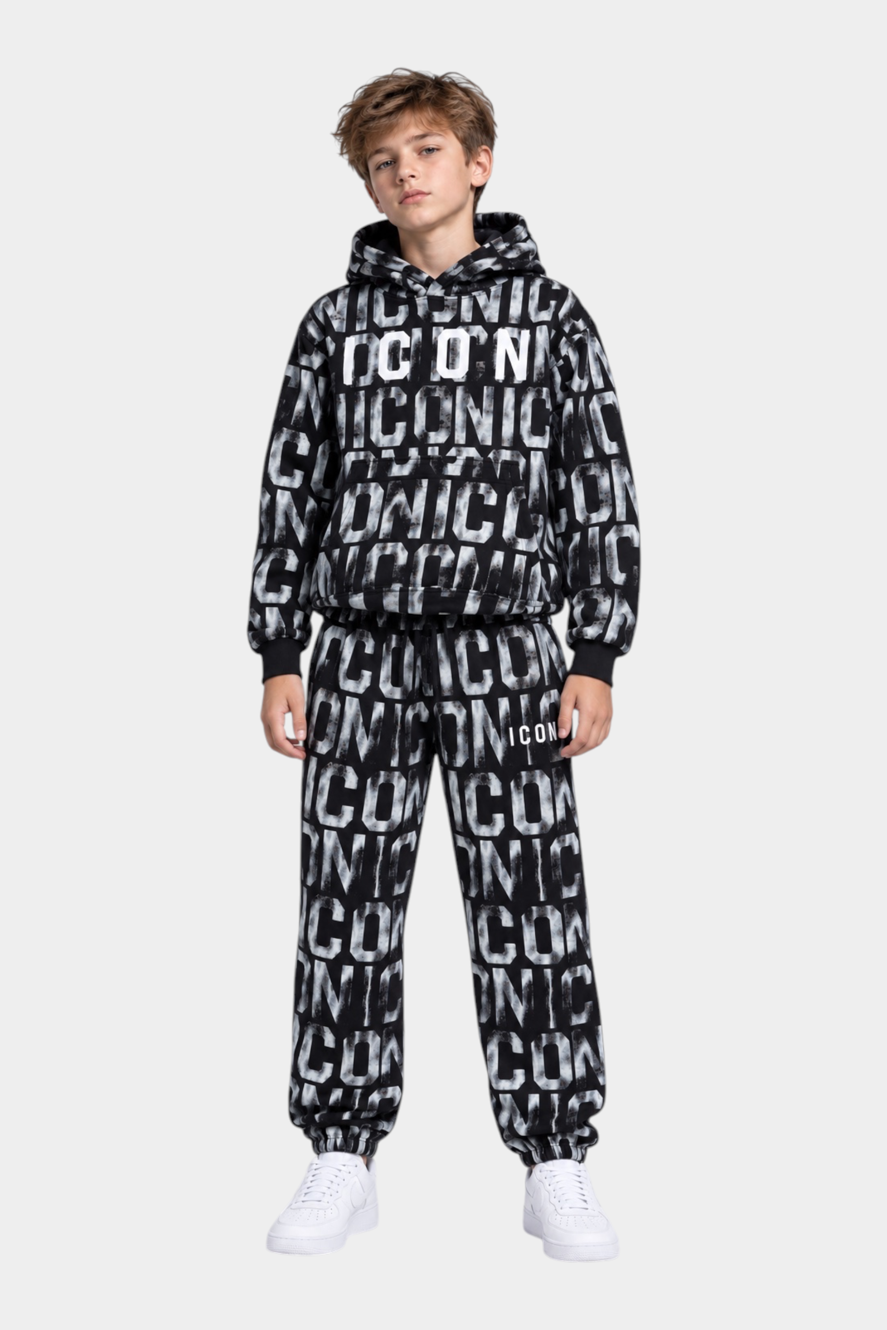 Ragazzo indossa una tuta Follower Official nera con stampa ICON bianca all-over, felpa con cappuccio e pantaloni jogger