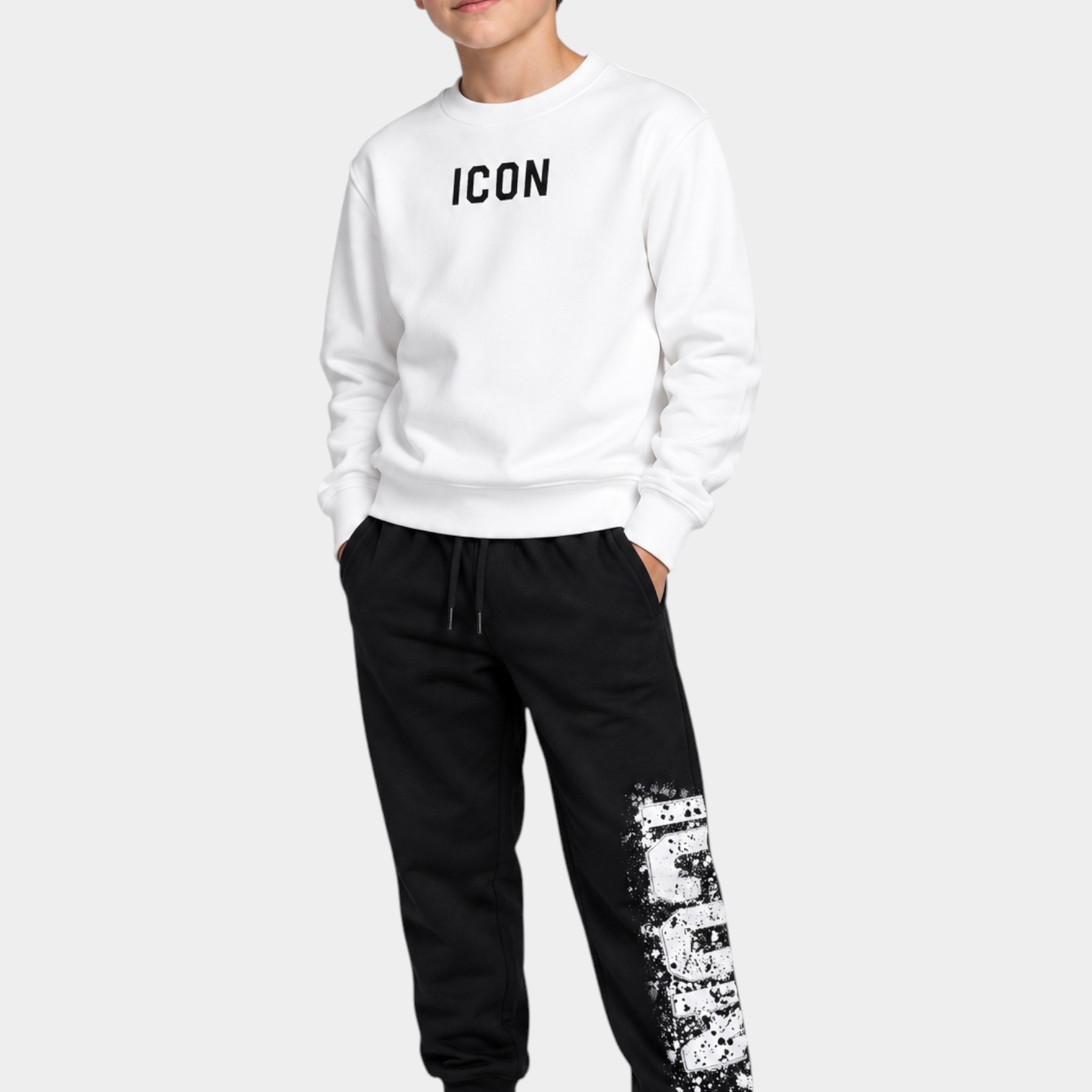 Ragazzo indossa felpa girocollo bianca Follower Official con scritta ICON nera e pantaloni neri con stampa effetto spray
