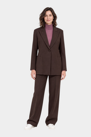 Modella indossa blazer marrone Follower SRL con rever a lancia, abbinato a pantaloni coordinati e maglia rosa