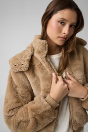 Modella indossa un bomber beige in pelliccia sintetica con cappuccio e polsini a coste, collezione Follower SRL