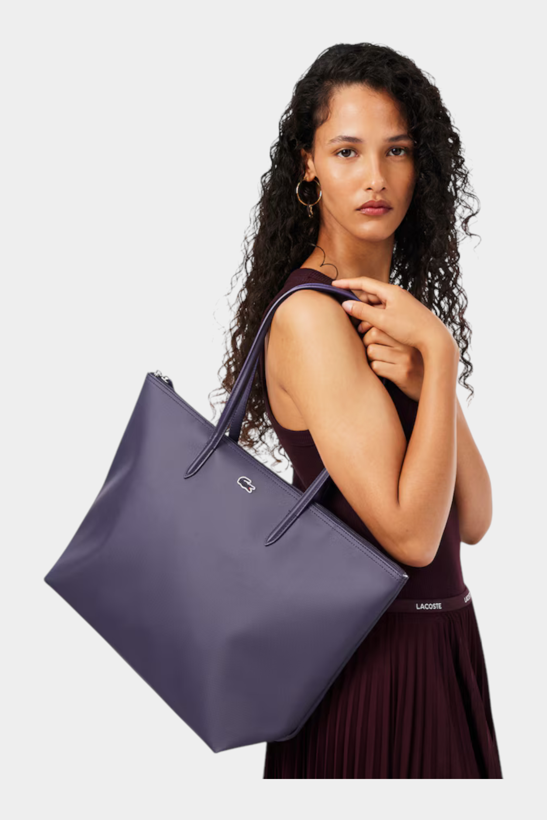 Modella indossa una borsa shopping grande viola Lacoste L.12.12 Concept di Follower SRL con finitura testurizzata
