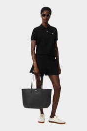 Modella indossa borsa tote nera con zip Anna di Follower SRL abbinata a polo e pantaloncini neri