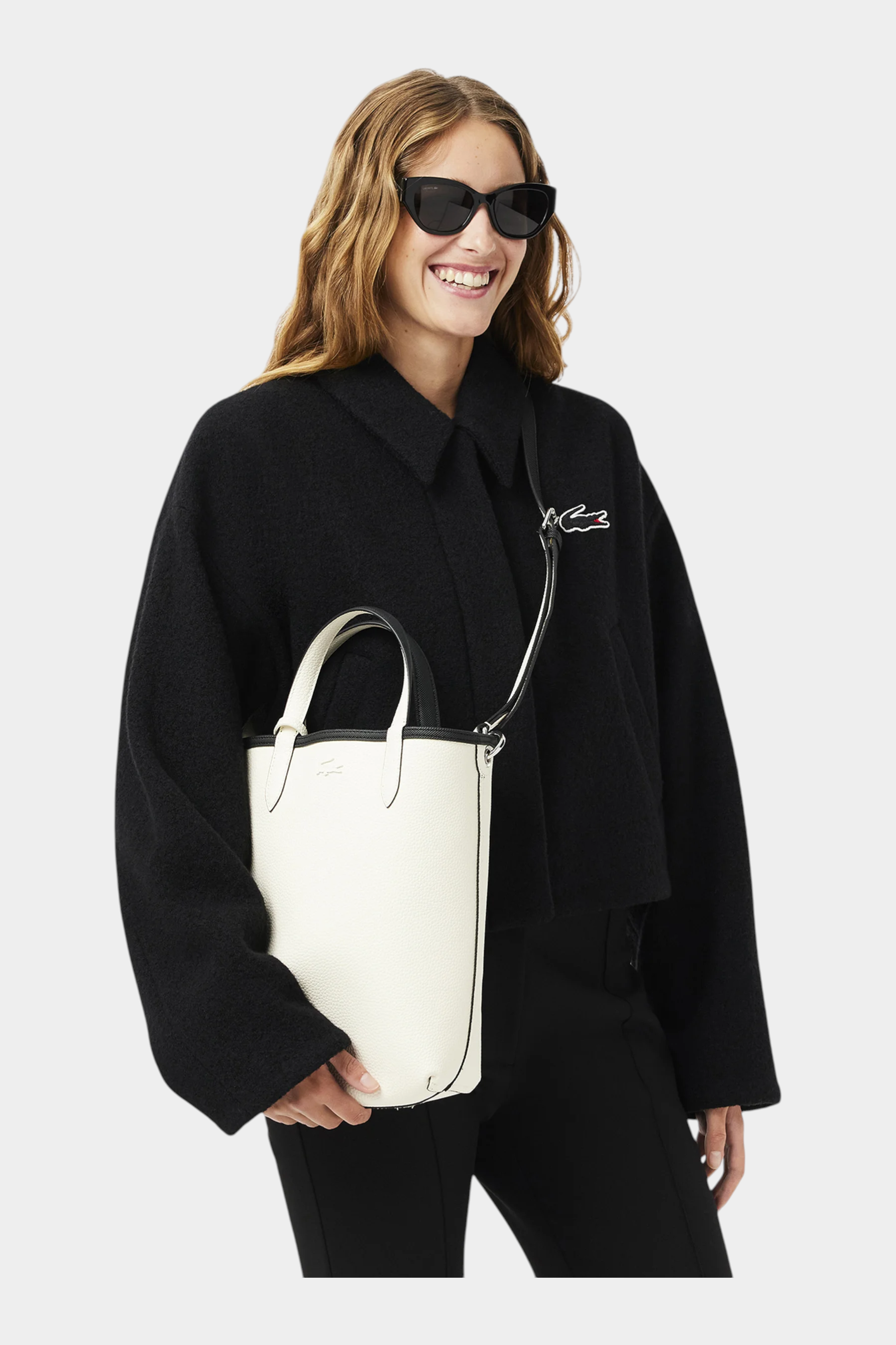 Modella indossa borsa da viaggio verticale reversibile Follower SRL LACOSTE bianca e nera con tracolla