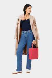 Modella indossa trench beige e jeans con borsa da viaggio verticale reversibile Follower SRL color rosa