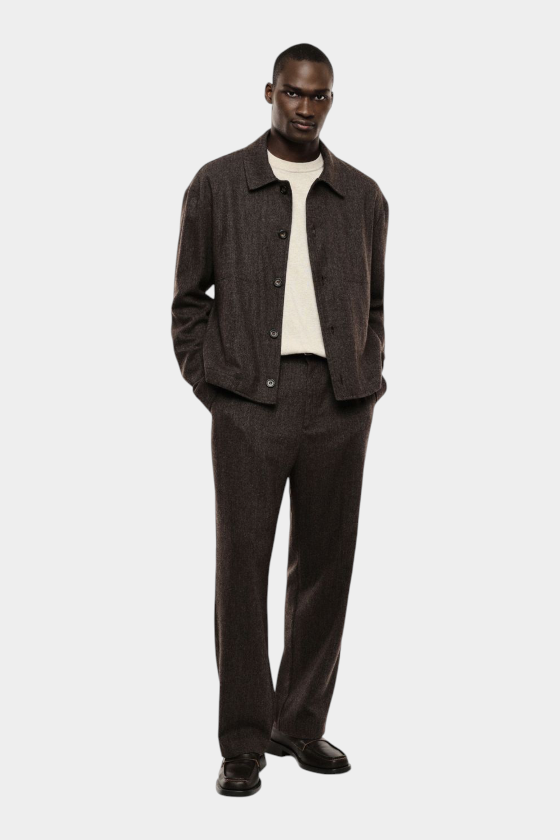 Modello indossa camicia marrone Follower SRL con colletto ampio e bottoni sopra maglia chiara e pantaloni abbinati