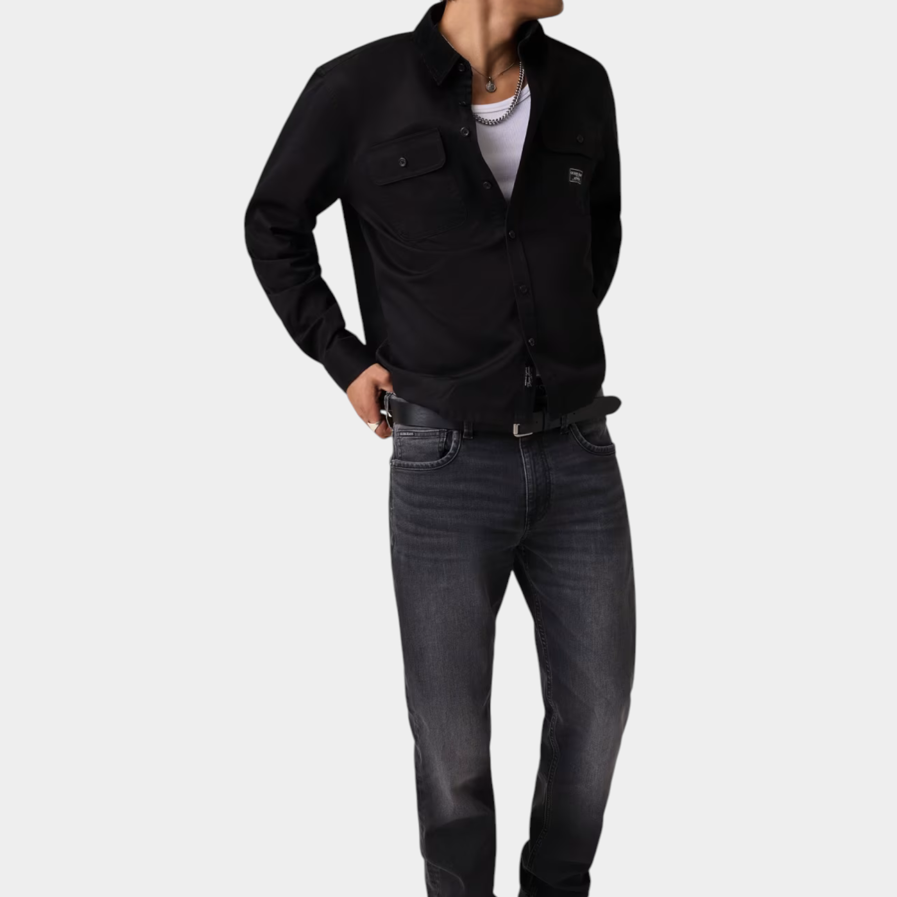 Modello indossa camicia nera regular-fit GUESS con taschini, abbinata a jeans grigi, proposta da Follower SRL