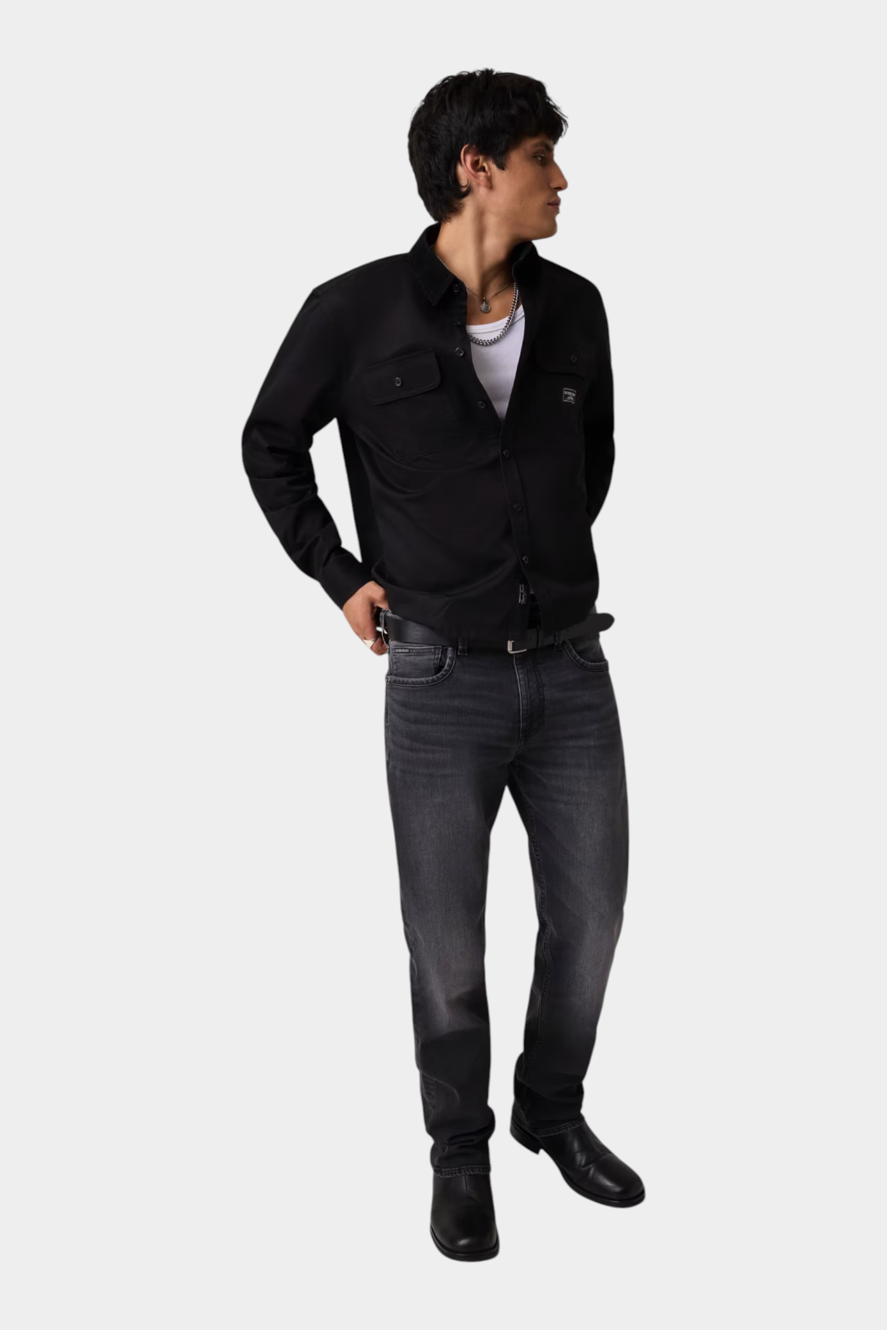 Modello indossa camicia nera regular-fit GUESS con taschini, abbinata a jeans grigi, proposta da Follower SRL