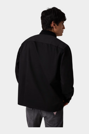 Vista posteriore di un uomo che indossa una camicia nera regular-fit GUESS di Follower SRL con jeans grigi