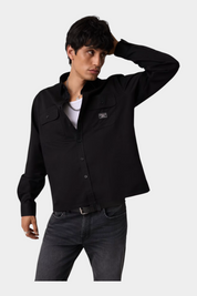 Modello indossa camicia nera regular-fit GUESS con tasche frontali, proposta da Follower SRL su sfondo neutro