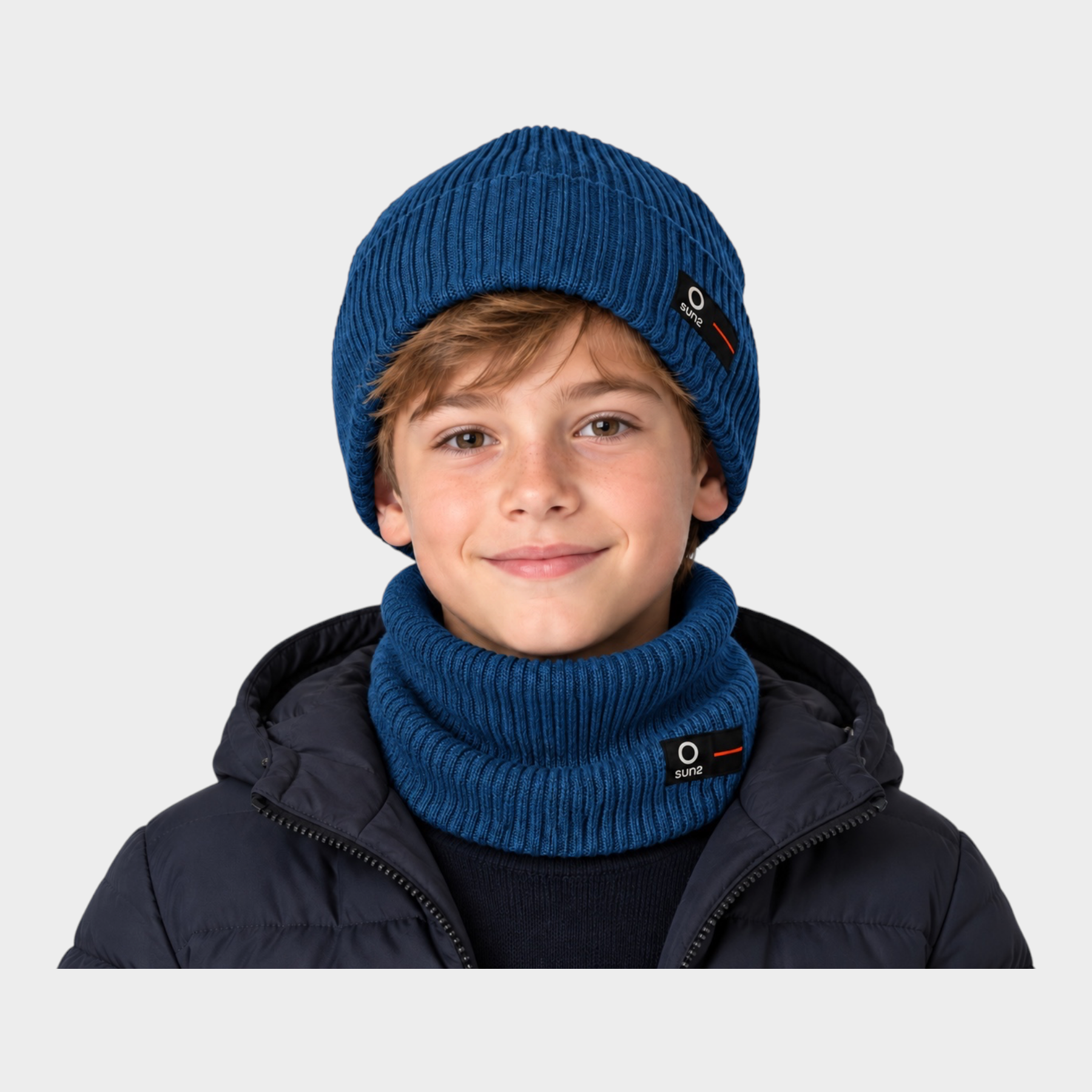 Ragazzo indossa cappello a cuffia e scaldacollo blu a costine Follower SRL con logo SUNS sul risvolto