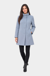 Modella indossa cappotto iconico Follower SRL azzurro con collo alto e chiusura a bottoni su sfondo neutro