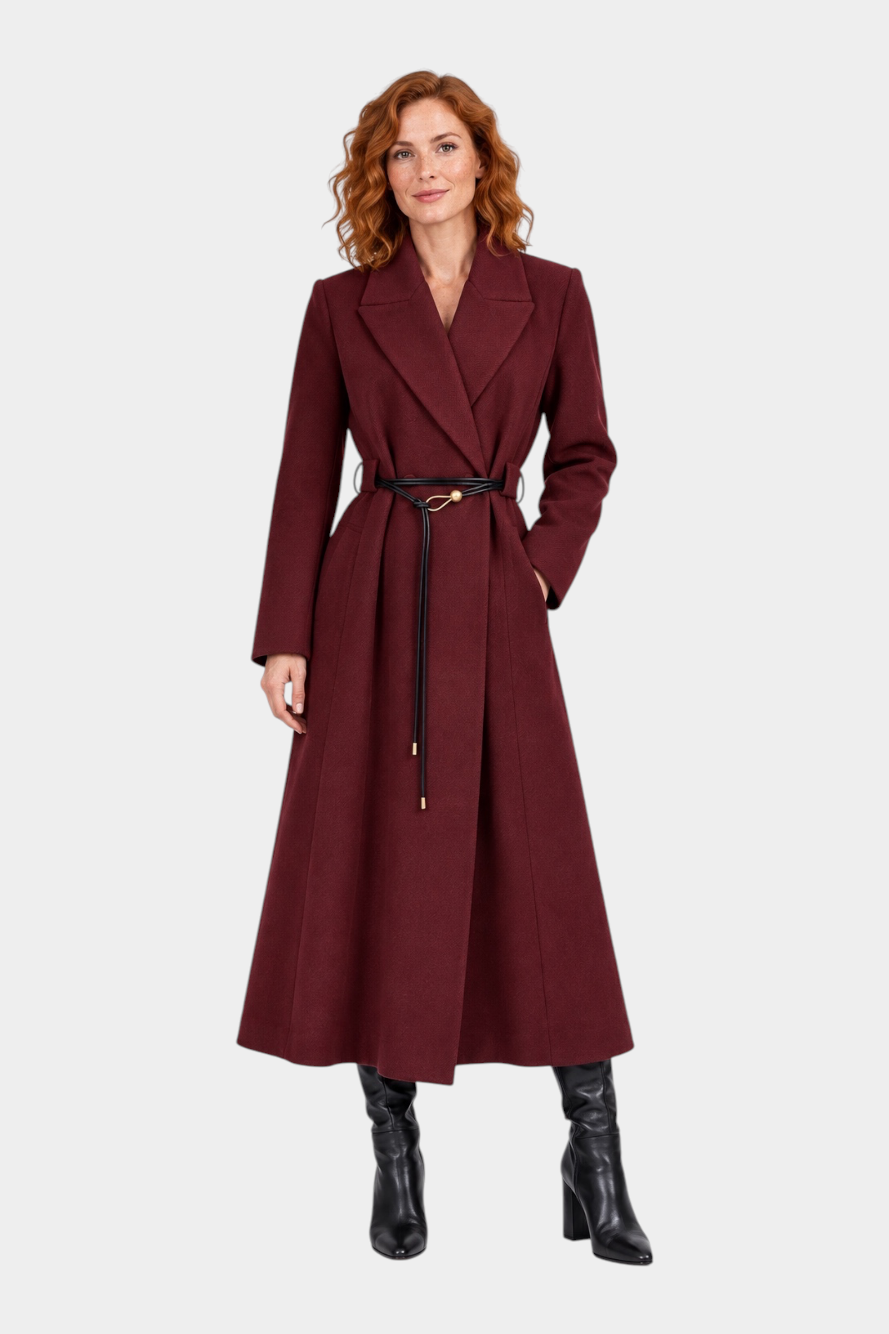 Modella indossa un cappotto lungo bordeaux Follower SRL con cintura sottile in vita e stivali neri