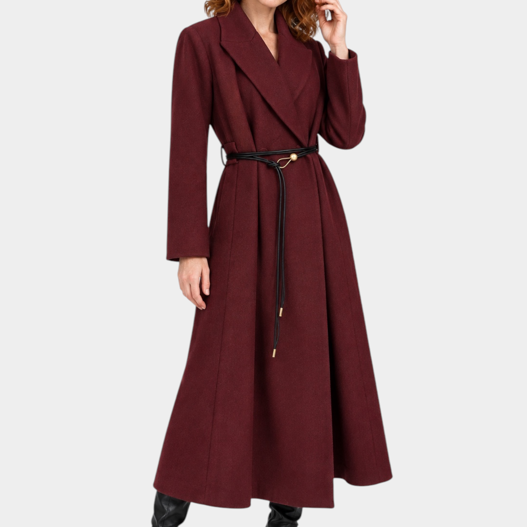 Modella indossa un cappotto lungo bordeaux Follower SRL con cintura sottile nera e stivali in pelle