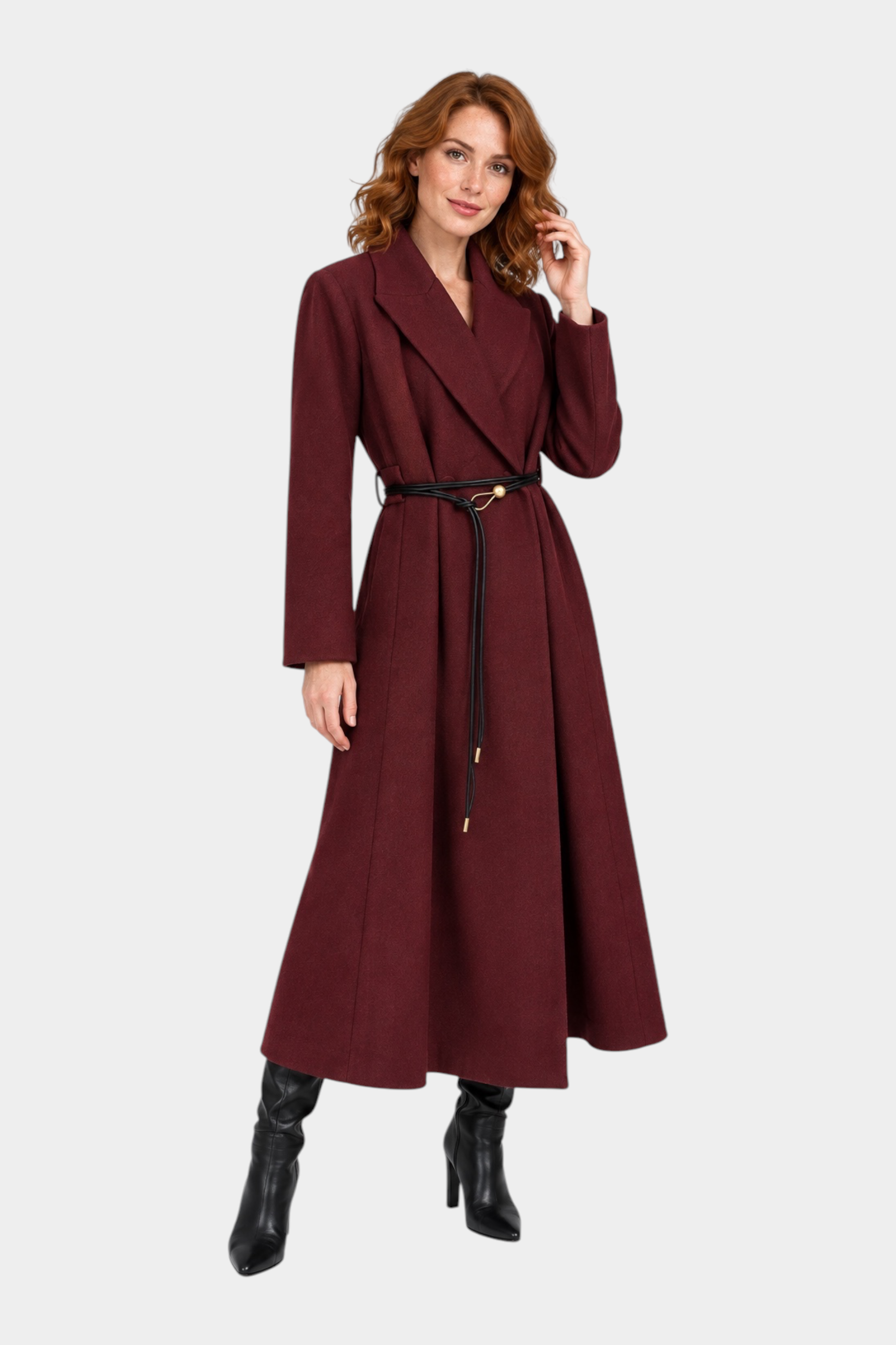 Modella indossa un cappotto lungo bordeaux Follower SRL con cintura sottile nera e stivali in pelle
