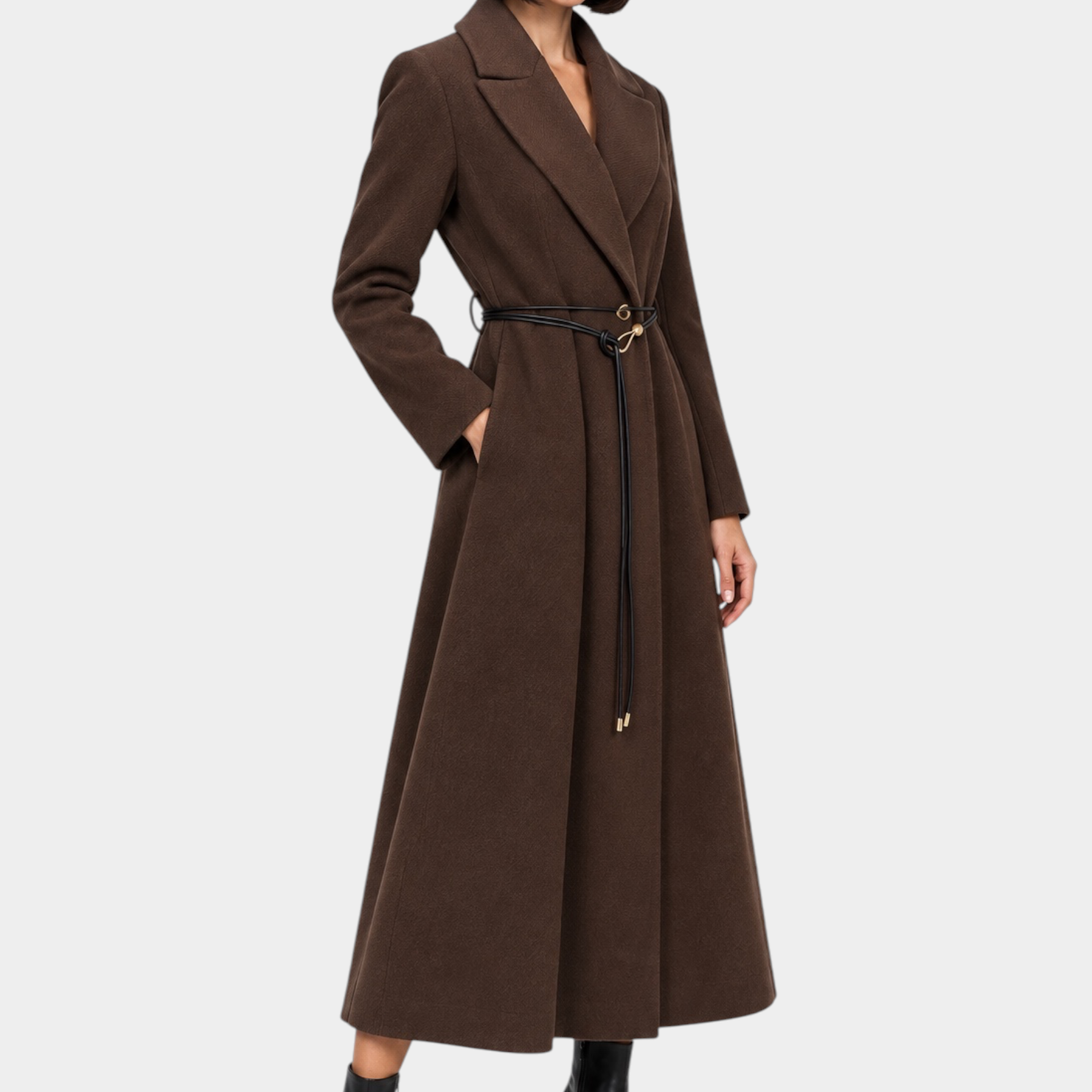 Modella indossa un cappotto lungo marrone Follower SRL con cintura in vita e stivaletti neri su sfondo neutro