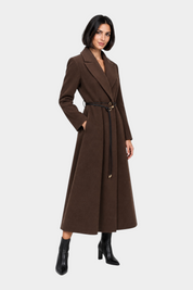 Modella indossa un cappotto lungo marrone Follower SRL con cintura in vita e stivaletti neri su sfondo neutro
