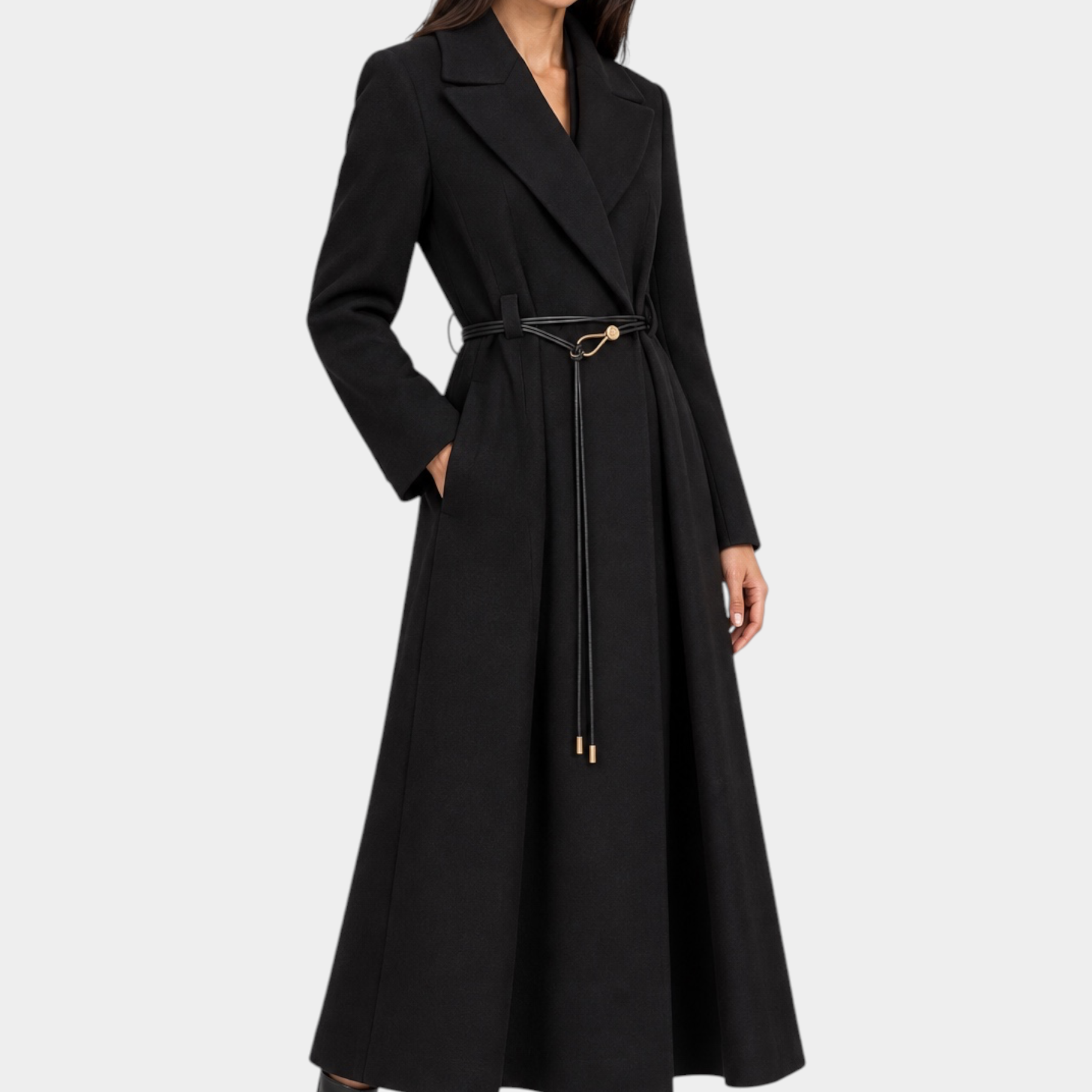 Modella indossa un cappotto lungo nero Follower SRL con cintura sottile in vita e revers ampi su fondo grigio