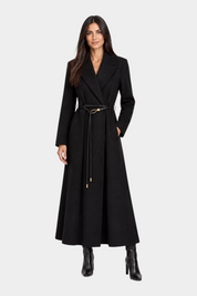 Modella indossa cappotto lungo nero Follower SRL con cintura sottile in vita e stivali coordinati