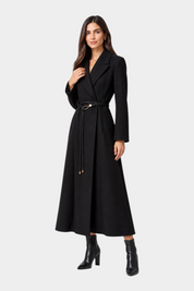 Modella indossa un cappotto lungo nero Follower SRL con cintura sottile in vita e stivaletti coordinati