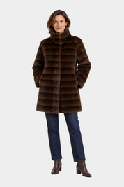 Modella indossa cappotto lungo reversibile marrone in ecopelliccia Follower SRL con colletto alto e jeans blu