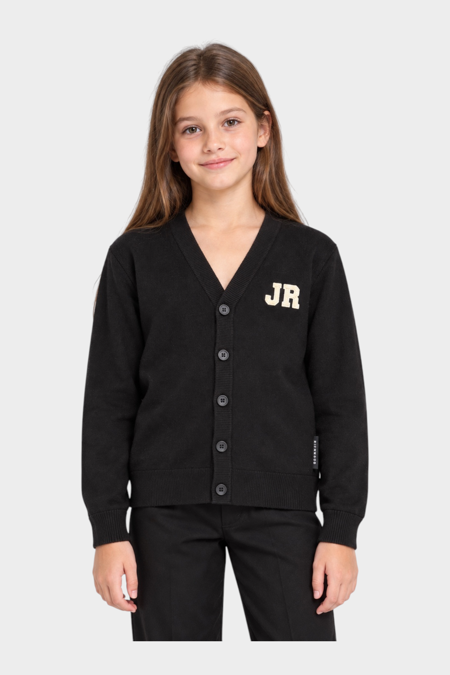 Bambina che indossa un cardigan nero Follower SRL con scollo a V, bottoni e logo JR ricamato sul petto