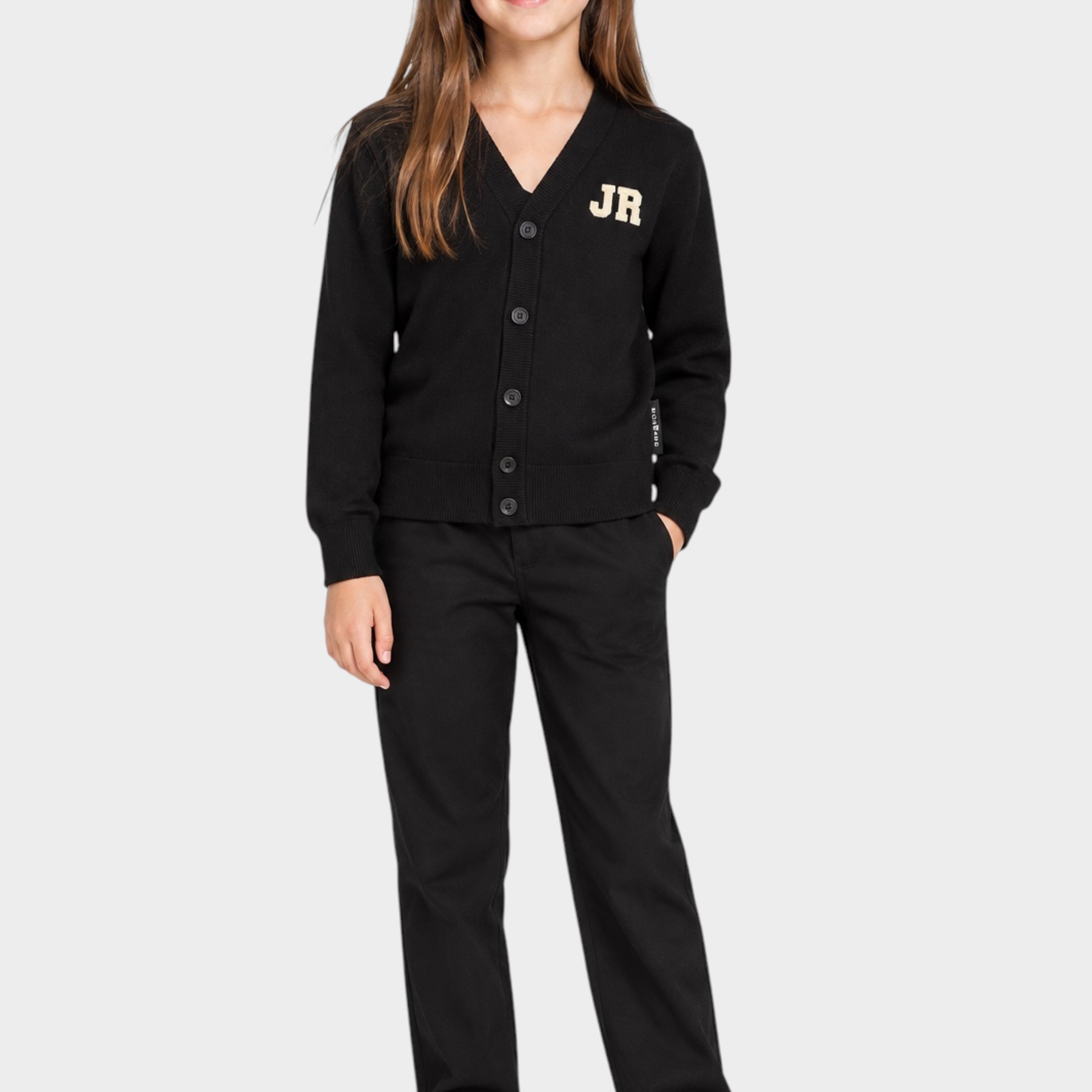 Bambina che indossa un cardigan nero Follower SRL con logo JR dorato, abbinato a pantaloni neri e scarpe bianche