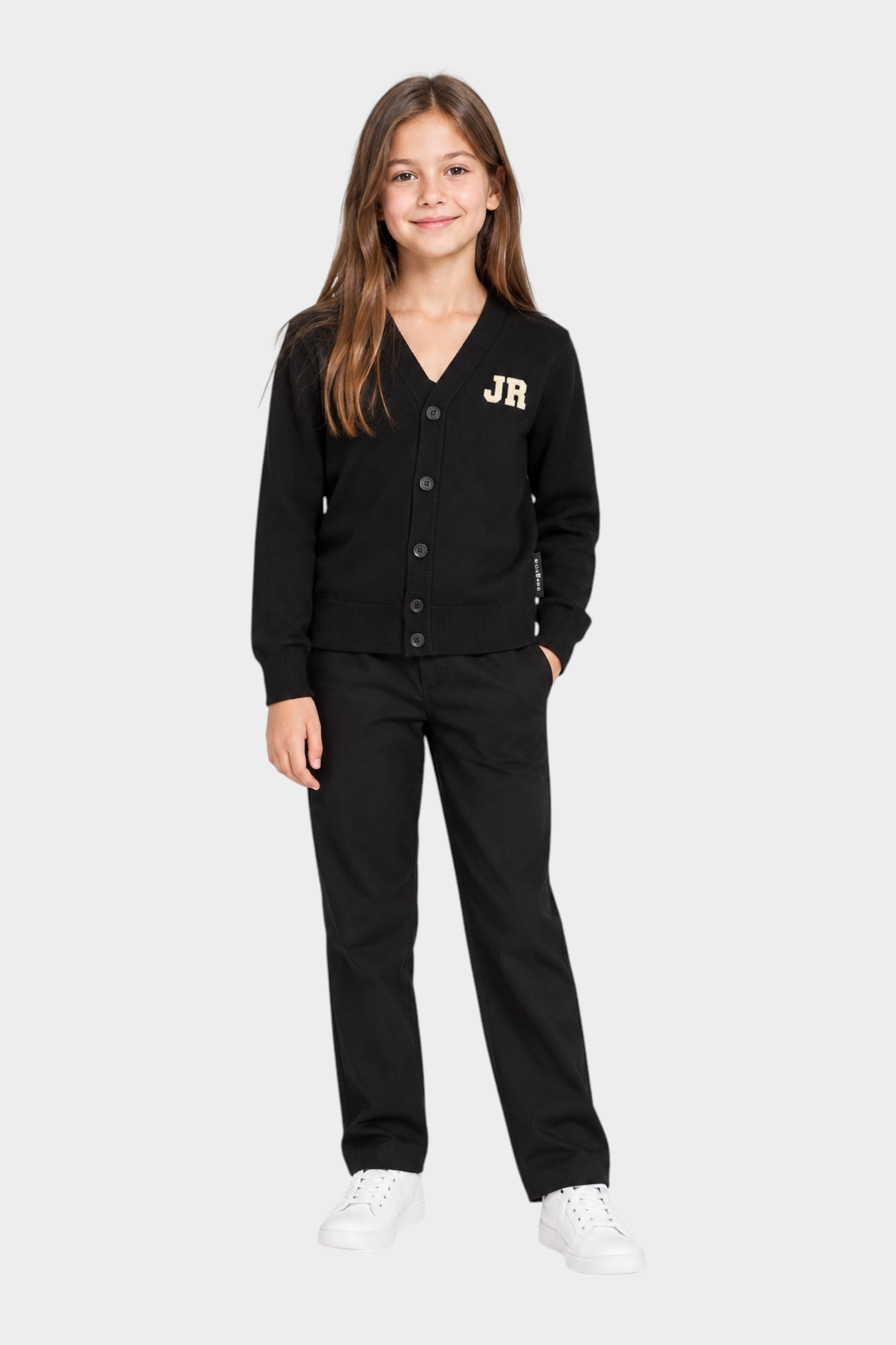 Bambina che indossa un cardigan nero Follower SRL con logo JR dorato, abbinato a pantaloni neri e scarpe bianche