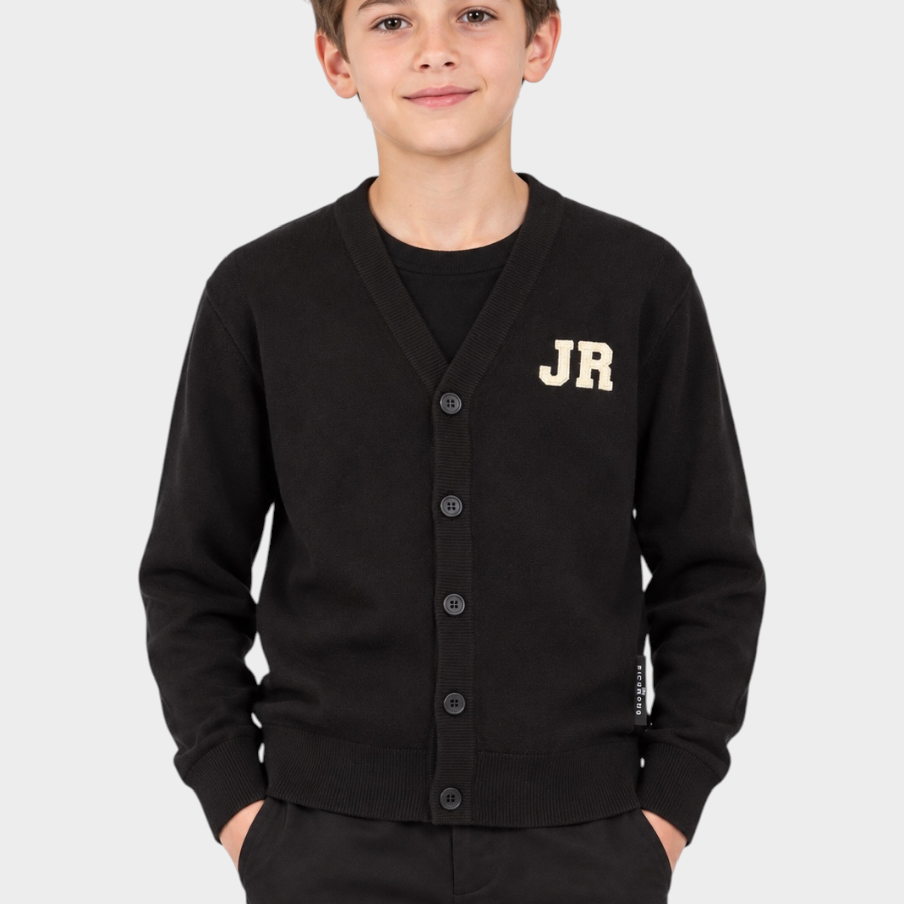 Ragazzo indossa cardigan nero Follower SRL con logo iconico JR bianco sul petto e chiusura a bottoni