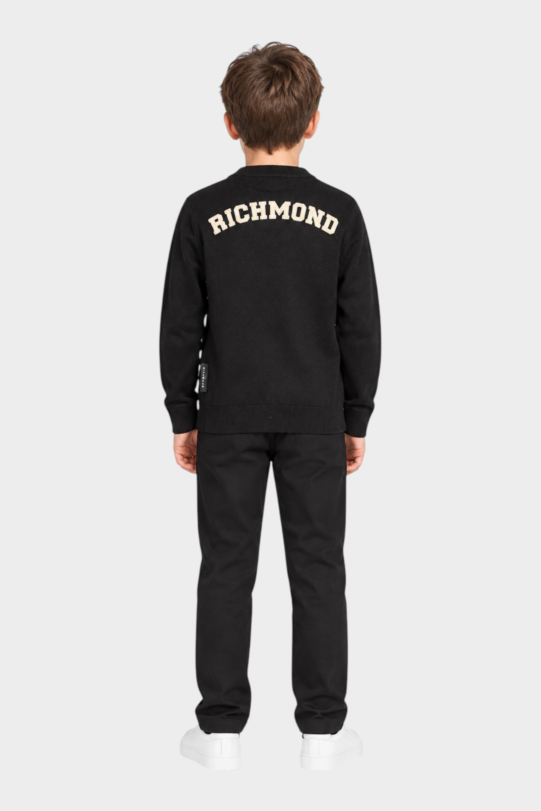 Ragazzo di spalle indossa un cardigan nero Follower SRL con logo RICHMOND bianco sulla schiena