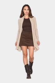 Modella indossa cardigan spolverino beige Follower SRL su top e gonna marroni con stivali scuri
