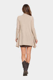 Modella di spalle indossa un cardigan spolverino beige Follower SRL con taglio svasato su sfondo neutro