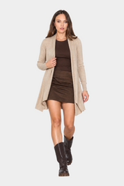 Modella indossa un cardigan spolverino beige Follower SRL aperto sopra un top e una minigonna marroni