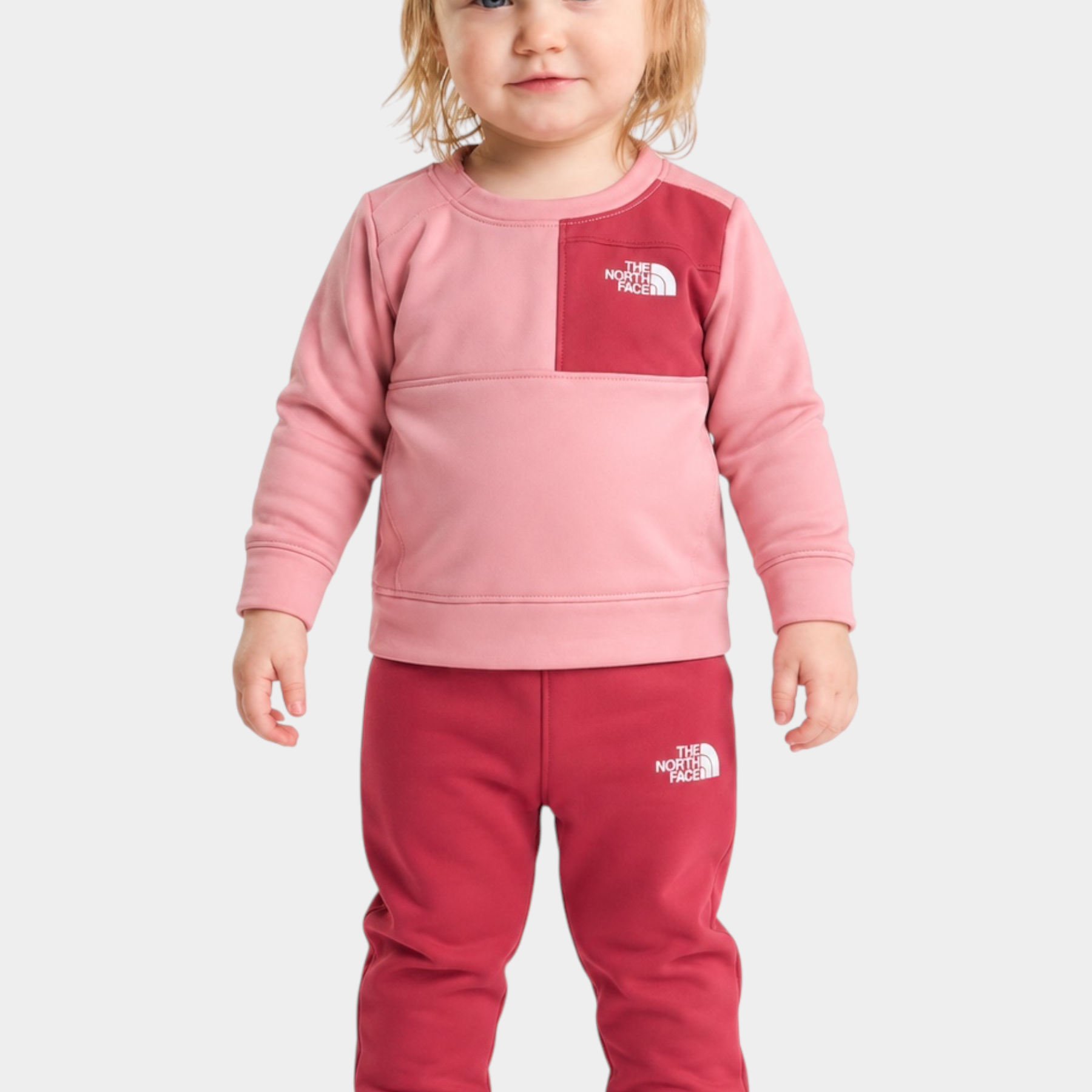 Bambina indossa completo due pezzi Follower SRL THE NORTH FACE rosa e rosso con felpa e pantaloni sportivi