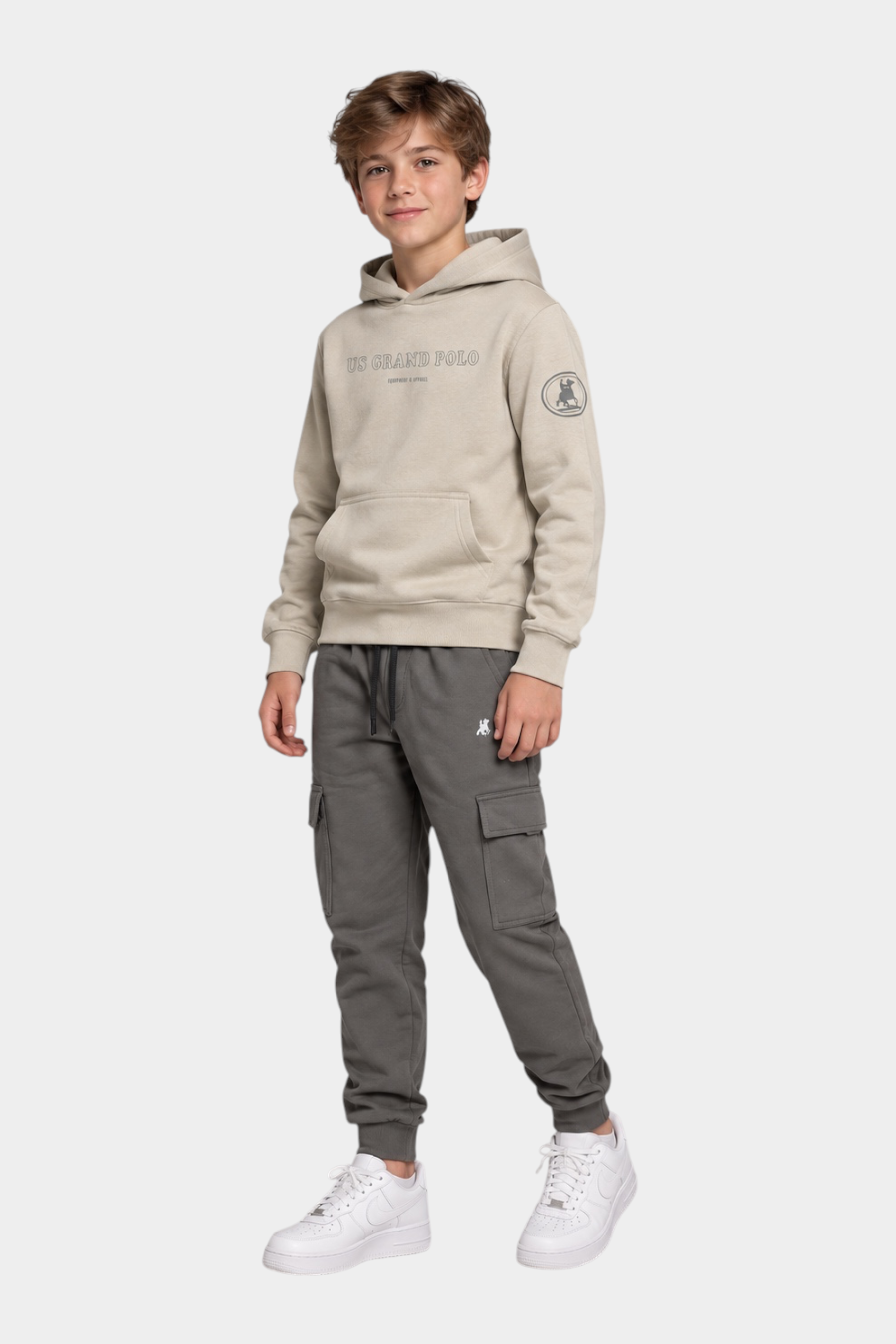 Ragazzo indossa completo Follower SRL con felpa beige con cappuccio US GRAND POLO e pantaloni cargo grigi