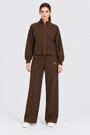 Modella indossa un completo Follower SRL marrone composto da giacca con zip e pantaloni jogger a gamba larga