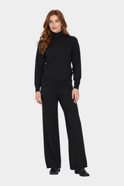 Modella indossa un completo Follower SRL nero con maglione a dolcevita e pantaloni a gamba larga in maglia