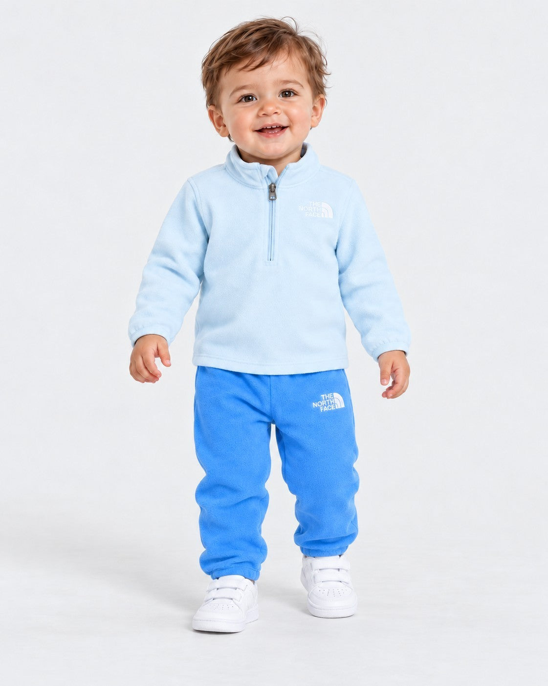 Bambino che indossa un completo due pezzi in pile azzurro Follower SRL con logo The North Face e zip frontale