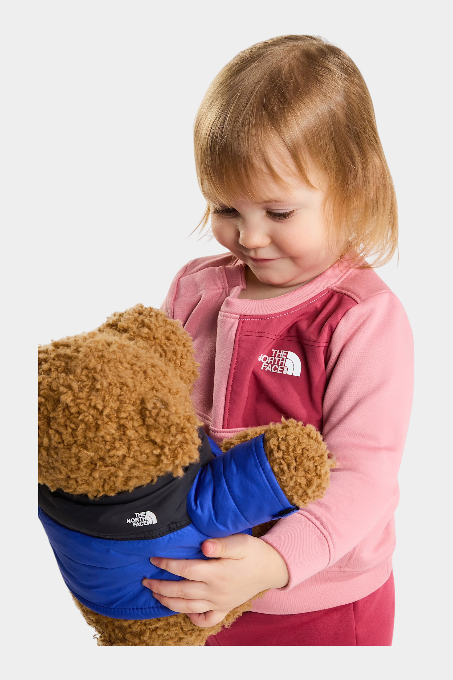 Bambina che indossa un completo due pezzi rosa THE NORTH FACE di Follower SRL mentre abbraccia un orsacchiotto