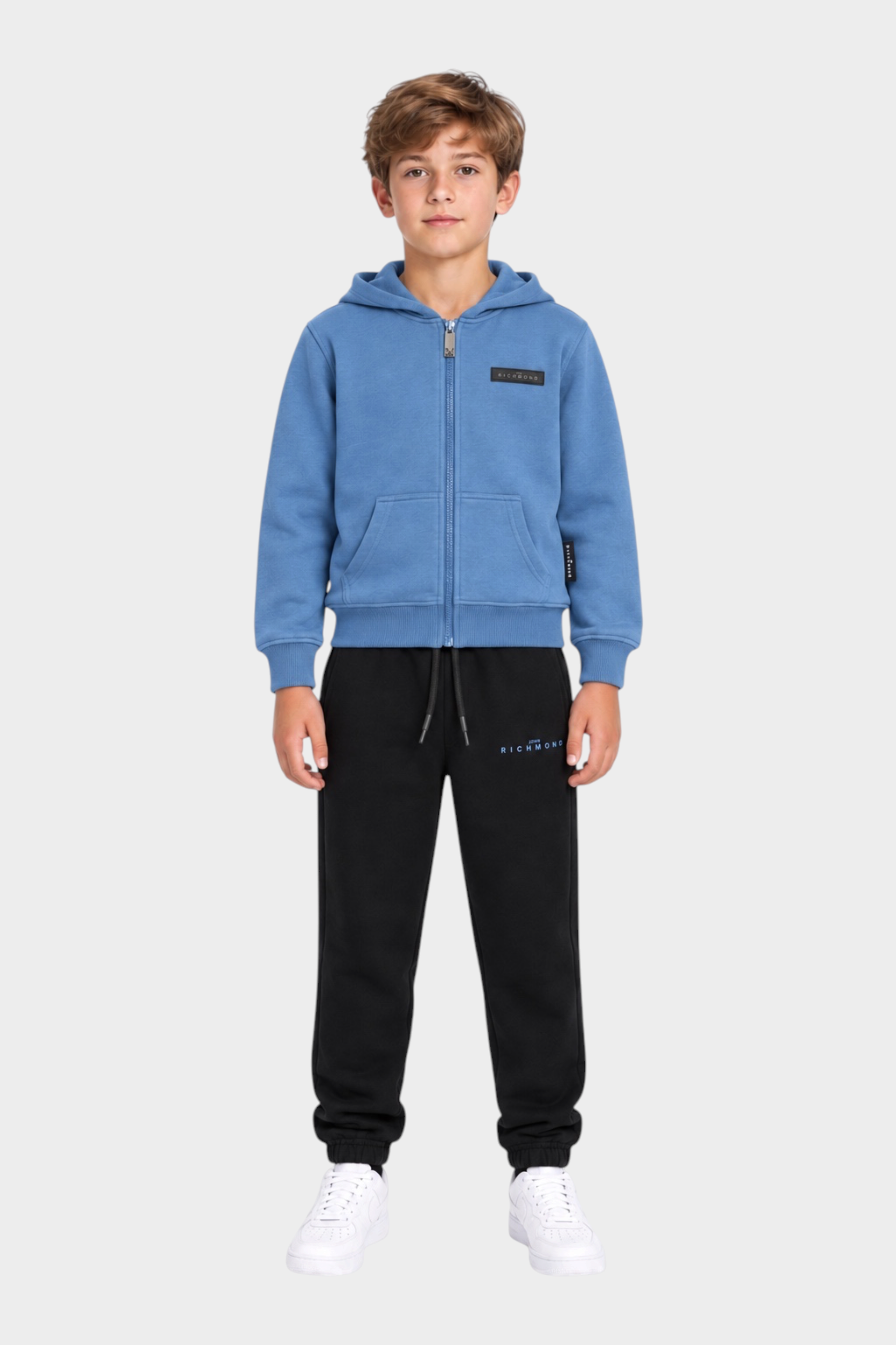 Ragazzo indossa completo sportivo Follower SRL azzurro con felpa con zip e pantaloni neri in cotone
