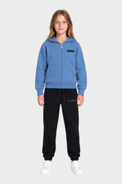 Ragazza indossa completo sportivo Follower SRL con felpa azzurra con zip e pantaloni neri in cotone