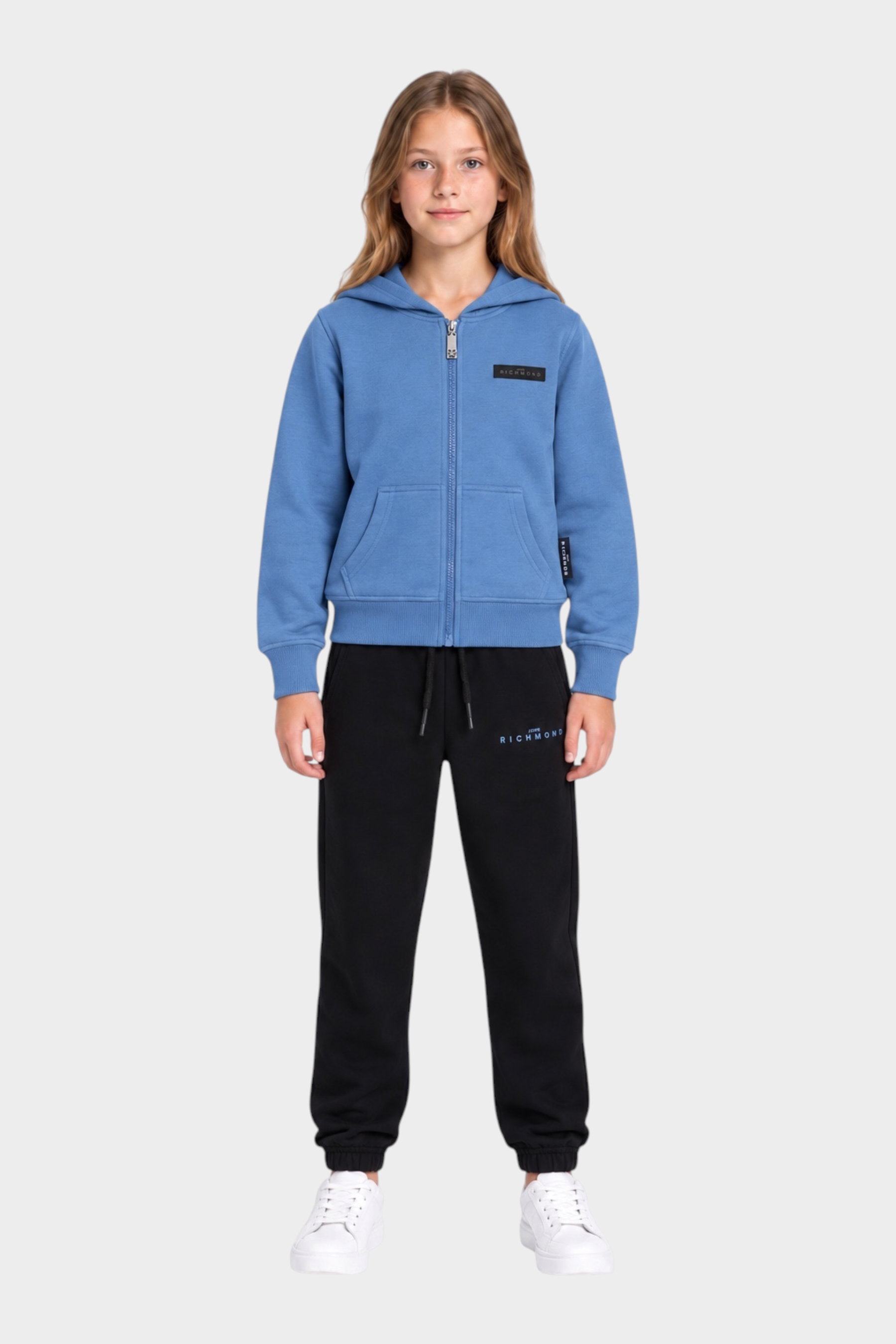 Ragazza indossa completo sportivo Follower SRL con felpa azzurra con zip e pantaloni neri in cotone