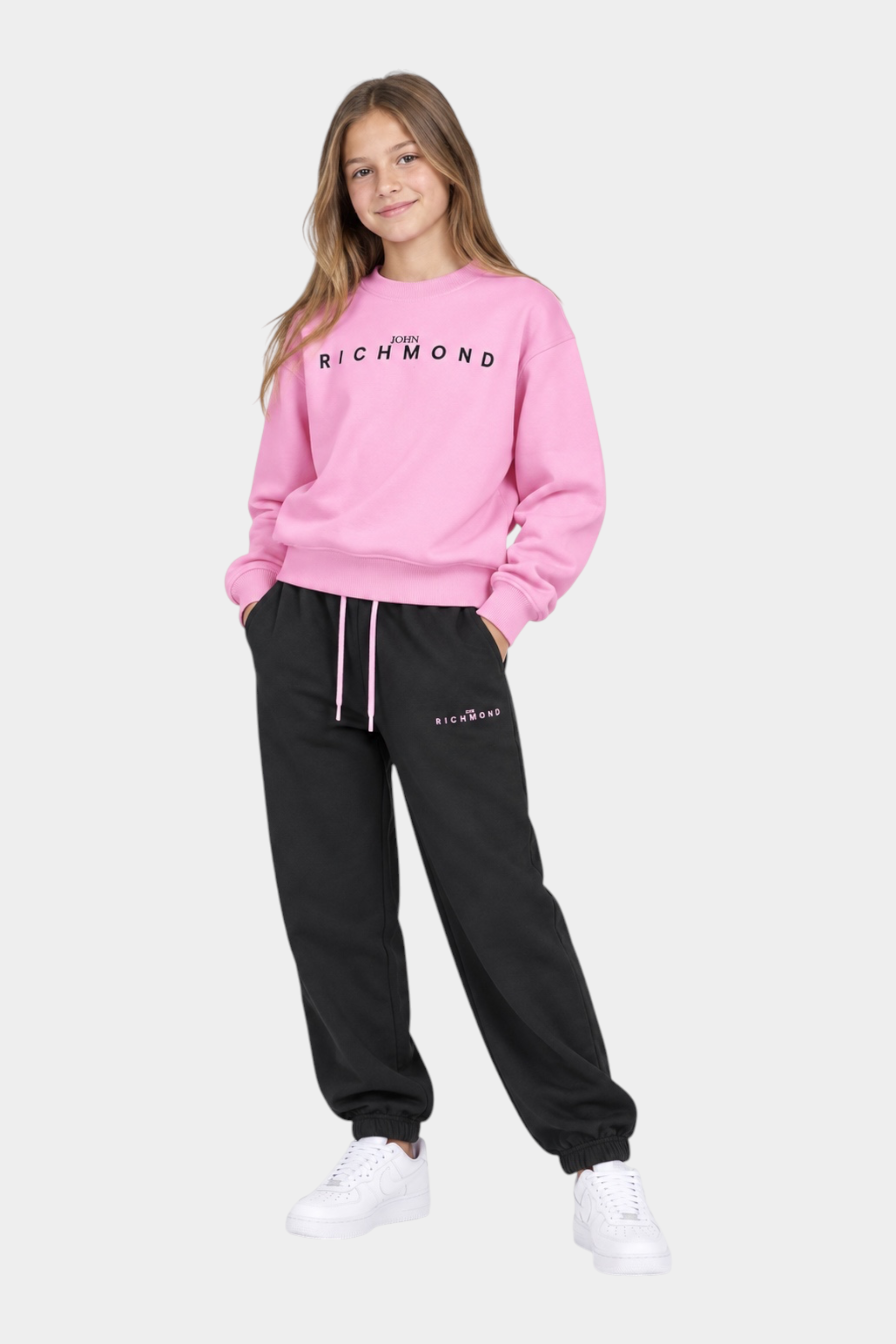 Ragazza indossa completo sportivo Follower SRL con felpa rosa e pantaloni neri con logo Richmond