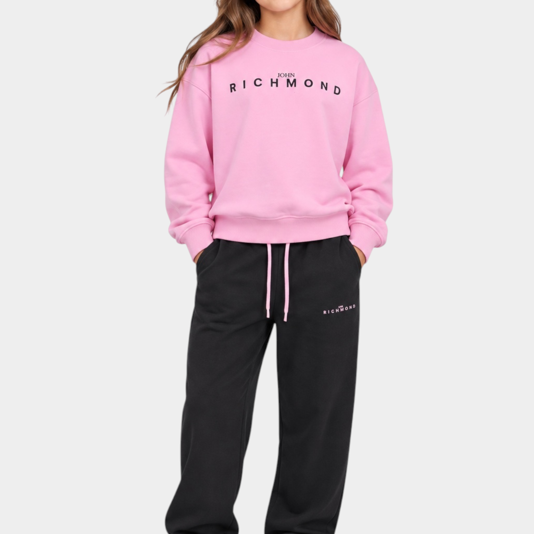 Ragazza indossa completo sportivo Follower SRL con felpa rosa e pantaloni neri con logo John Richmond