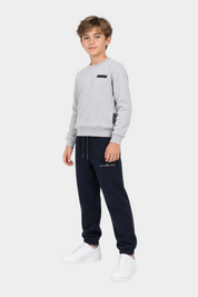 Ragazzo indossa completo sportivo Follower SRL con felpa grigia girocollo e pantaloni della tuta blu scuro