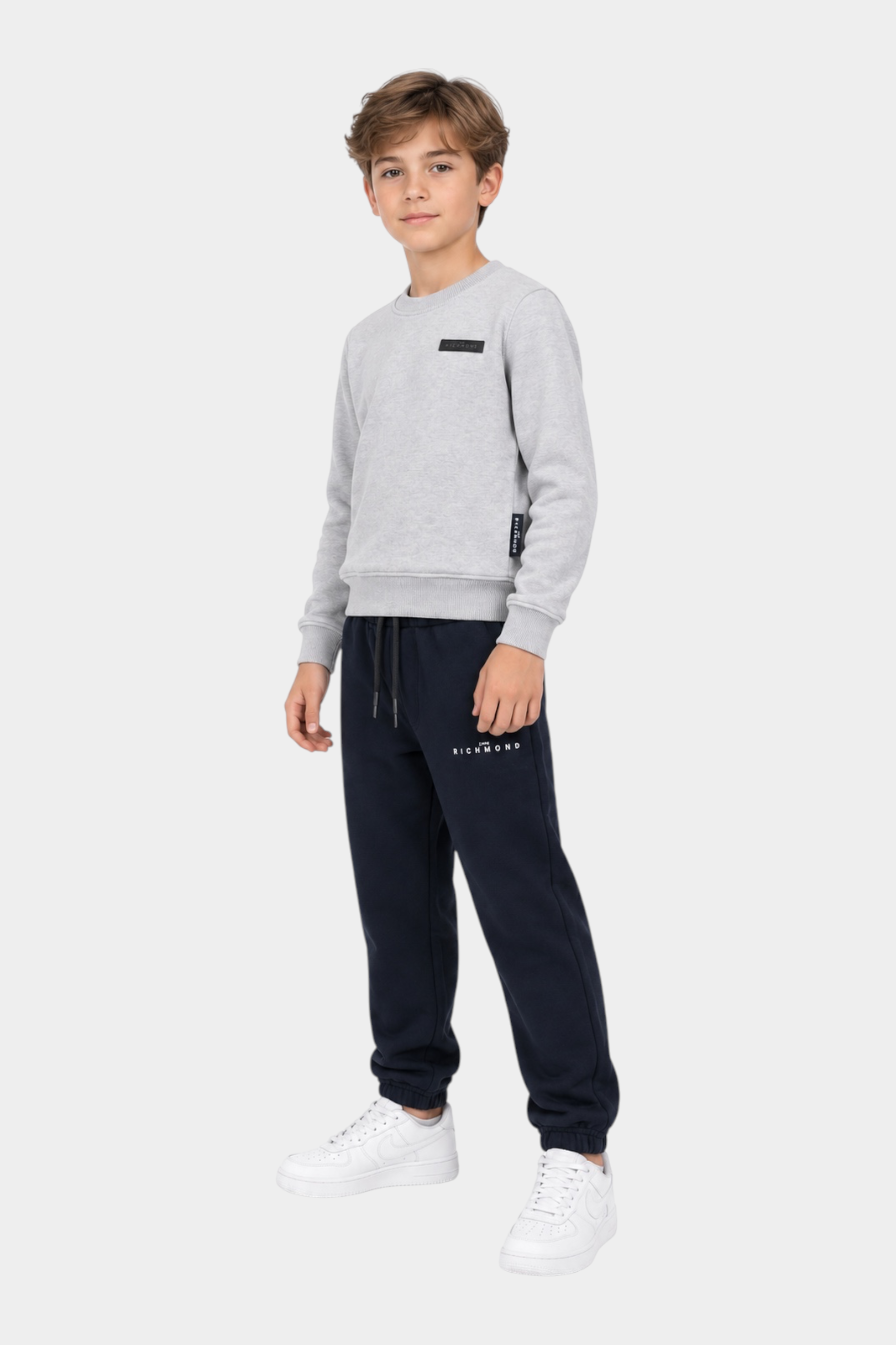 Ragazzo indossa completo sportivo Follower SRL con felpa grigia girocollo e pantaloni della tuta blu scuro