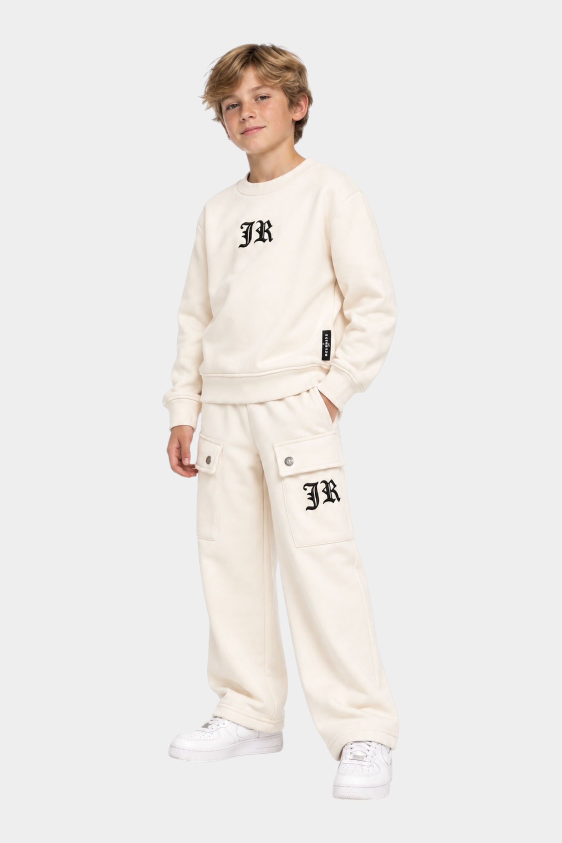Ragazzo indossa completo sportivo Follower SRL beige con felpa girocollo e pantaloni cargo con logo JR nero